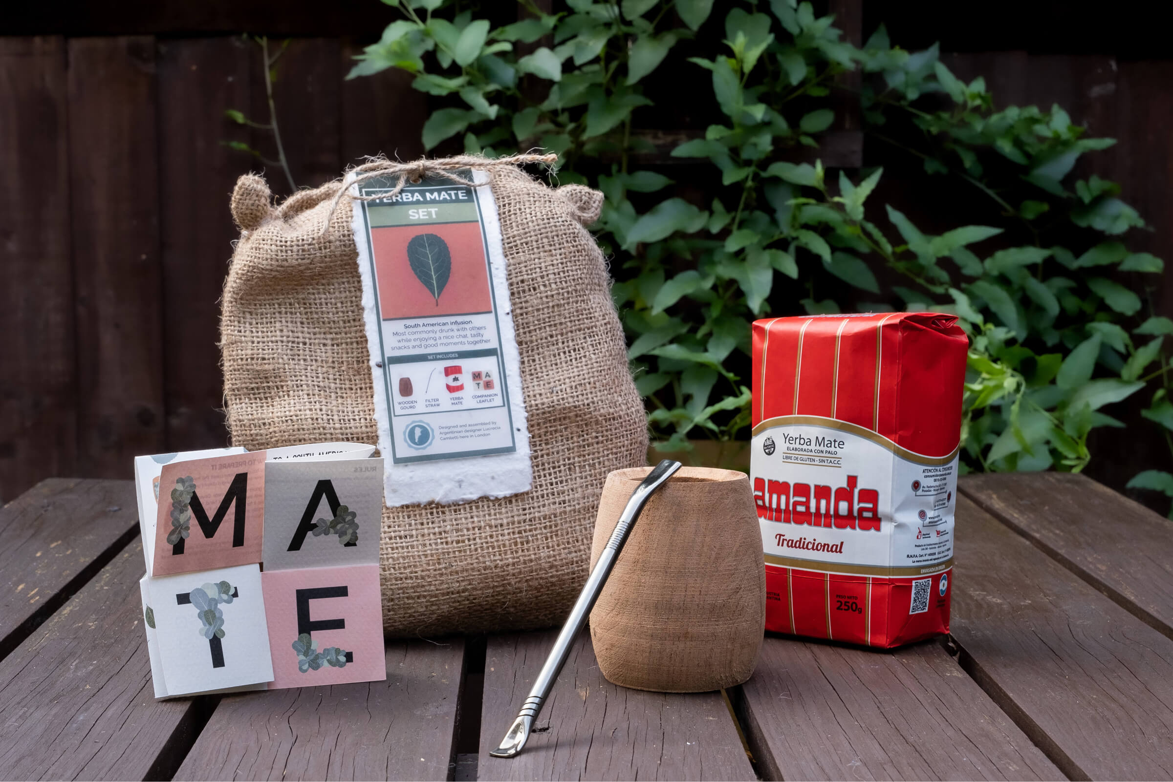 The burlap bag, leaflet, wooden gourd and a pack of yerba mate, photographed outdoors on a wooden table